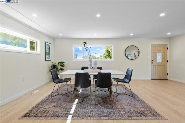 dining space featuring a wealth of natural light, ornamental molding, and light wood-type flooring