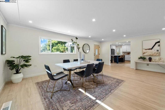 dining area with crown molding and light hardwood / wood-style flooring