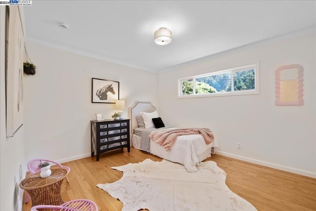 bedroom with crown molding and light hardwood / wood-style floors