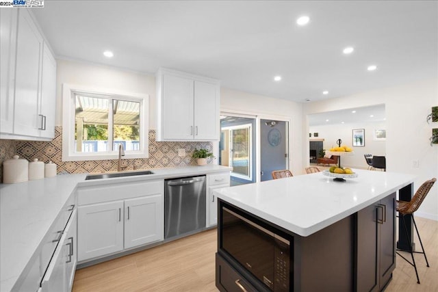 kitchen featuring white cabinets, light hardwood / wood-style flooring, stainless steel dishwasher, and sink