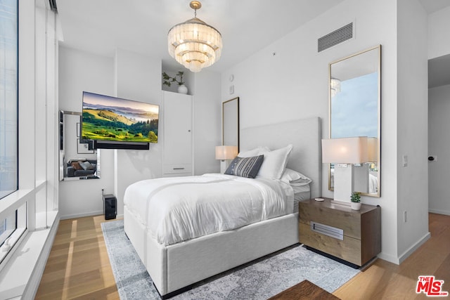 bedroom with an inviting chandelier and light wood-type flooring