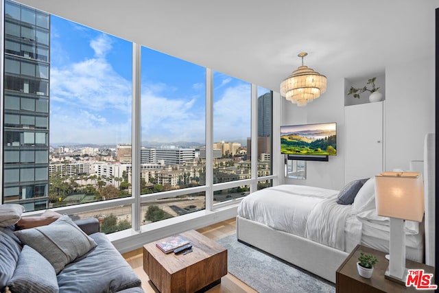 bedroom featuring an inviting chandelier, a wall of windows, and hardwood / wood-style floors