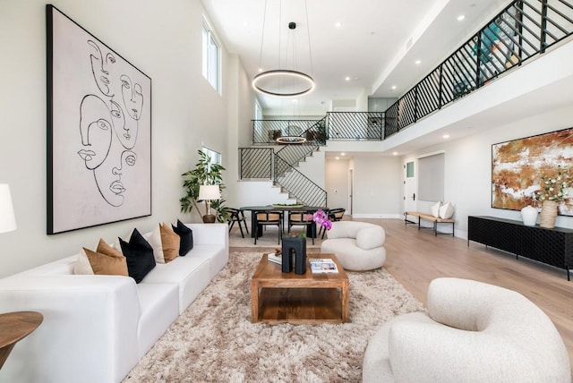 living room with a towering ceiling and light hardwood / wood-style flooring