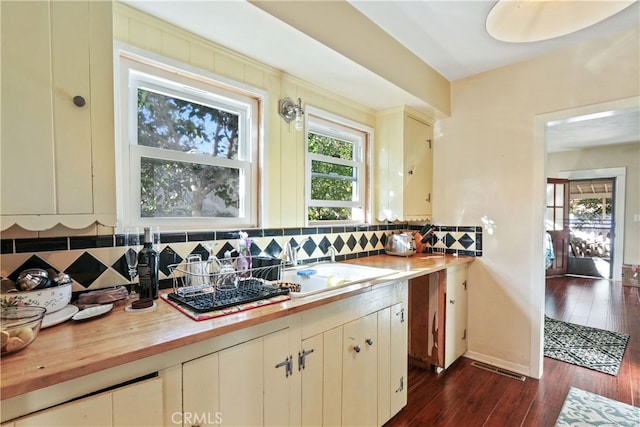 kitchen with sink, dark wood-type flooring, butcher block counters, and decorative backsplash