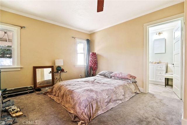 carpeted bedroom with crown molding, ensuite bath, and ceiling fan