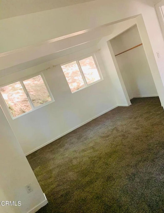 bonus room with vaulted ceiling and dark colored carpet