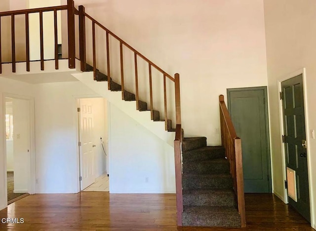 stairway with a towering ceiling and hardwood / wood-style floors