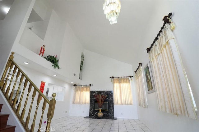 unfurnished living room featuring high vaulted ceiling, a fireplace, an inviting chandelier, and stairs