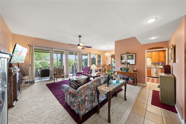 tiled living room with ceiling fan with notable chandelier