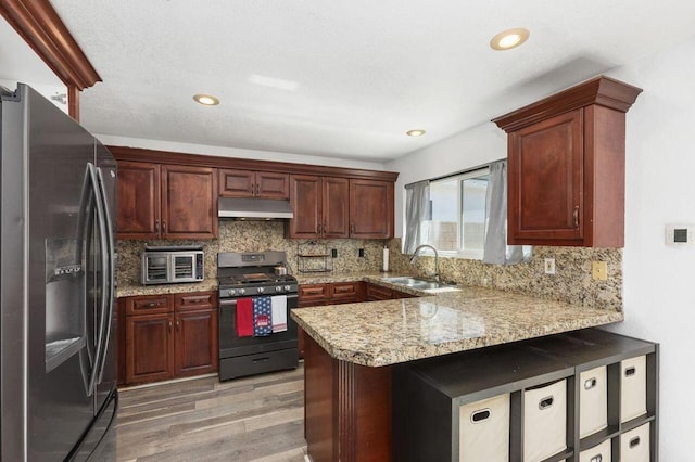 kitchen with stainless steel appliances, light hardwood / wood-style floors, sink, backsplash, and kitchen peninsula