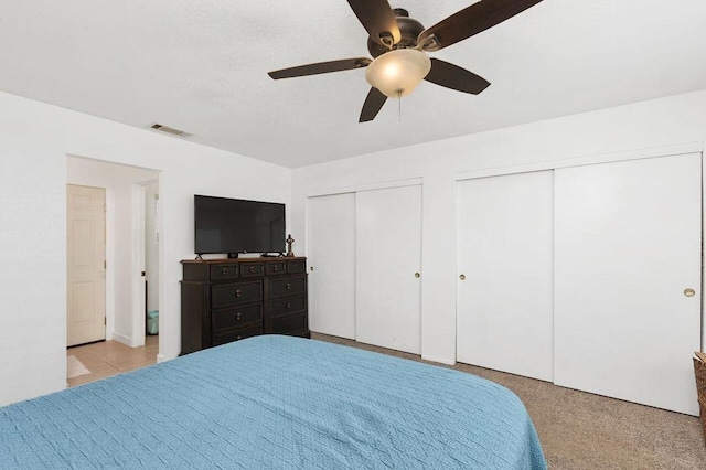 bedroom with ceiling fan and two closets