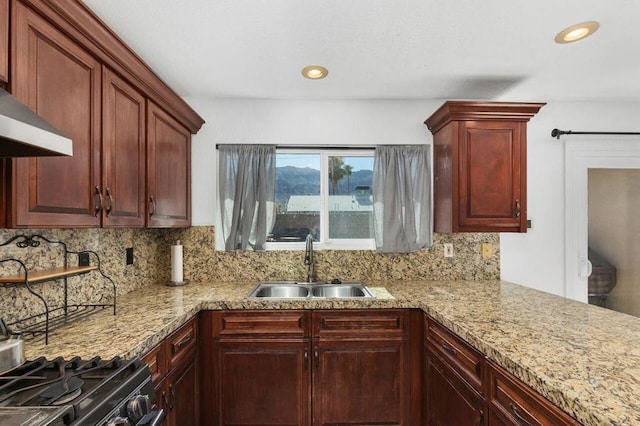 kitchen featuring decorative backsplash, sink, light stone counters, and wall chimney exhaust hood