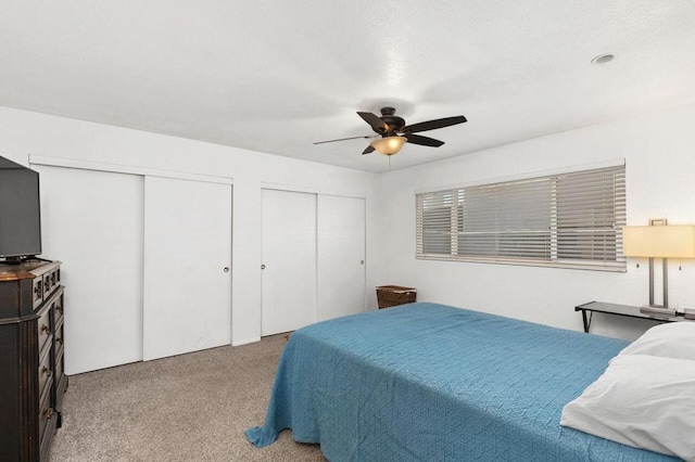 carpeted bedroom featuring ceiling fan and multiple closets