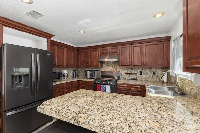 kitchen with light stone countertops, stainless steel appliances, tasteful backsplash, sink, and kitchen peninsula