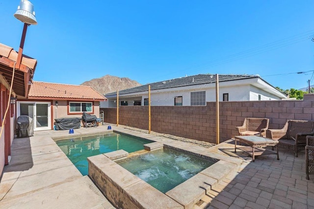 view of pool with an in ground hot tub, a patio area, and a mountain view