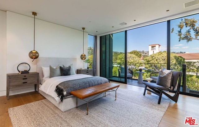 bedroom with wood-type flooring, access to exterior, and floor to ceiling windows