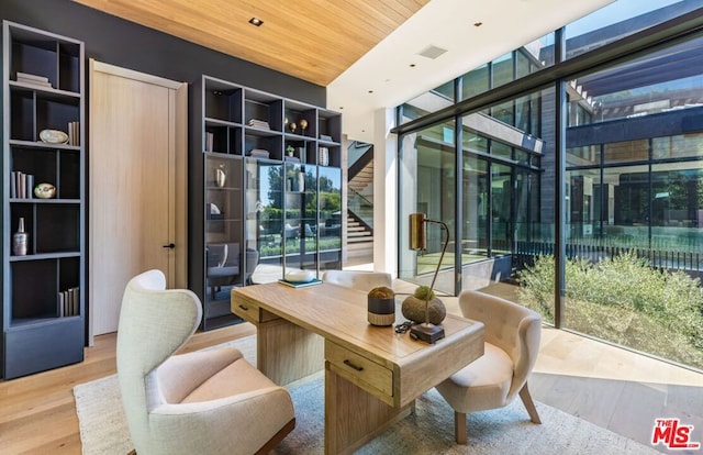 office area with hardwood / wood-style flooring, wooden ceiling, floor to ceiling windows, and a healthy amount of sunlight