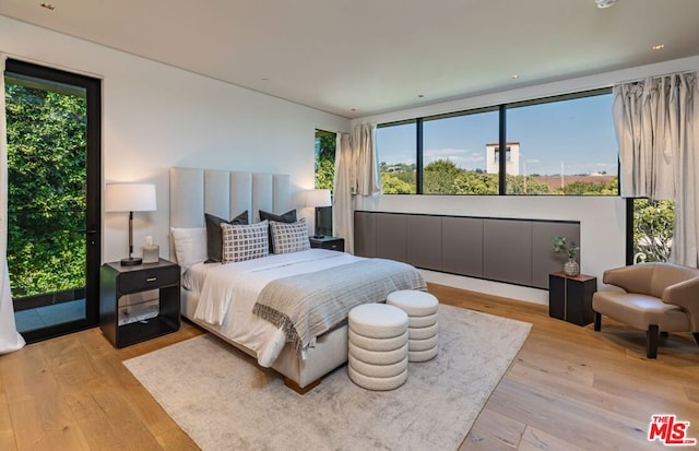 bedroom featuring access to outside, multiple windows, and light hardwood / wood-style flooring