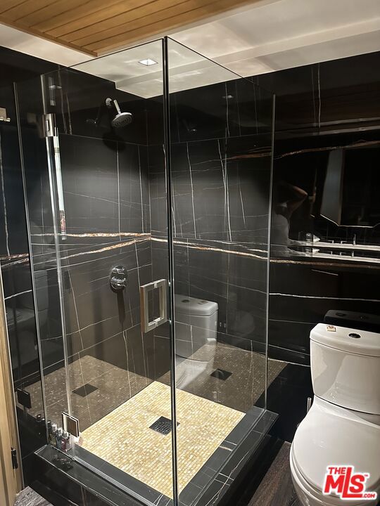 bathroom with toilet and an enclosed shower