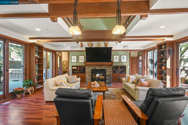 living room with beam ceiling, dark hardwood / wood-style floors, and a stone fireplace