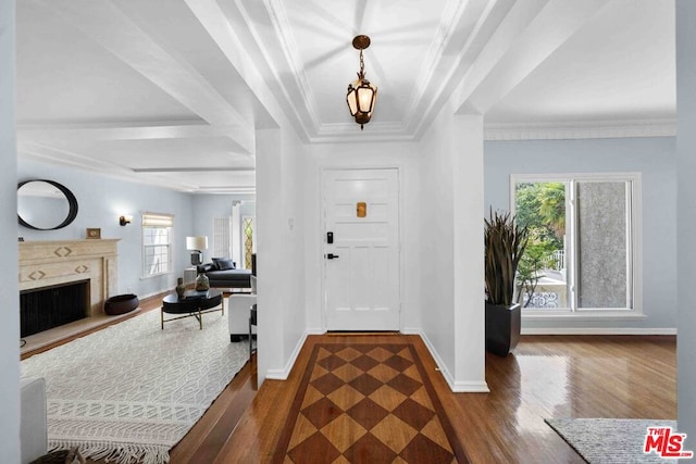 foyer entrance with dark wood-type flooring, a wealth of natural light, ornamental molding, and a fireplace