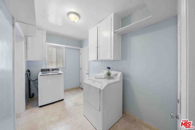 clothes washing area with cabinets and washer and clothes dryer