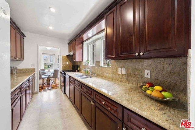 kitchen with light stone countertops, gas range oven, tasteful backsplash, and sink