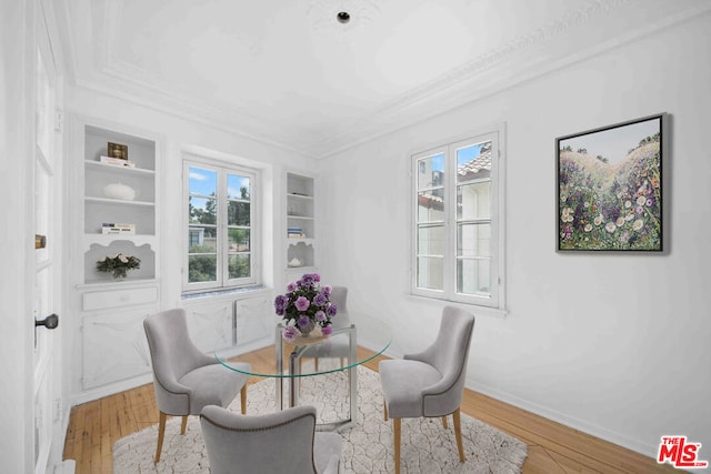 dining area featuring crown molding, a healthy amount of sunlight, wood-type flooring, and built in shelves