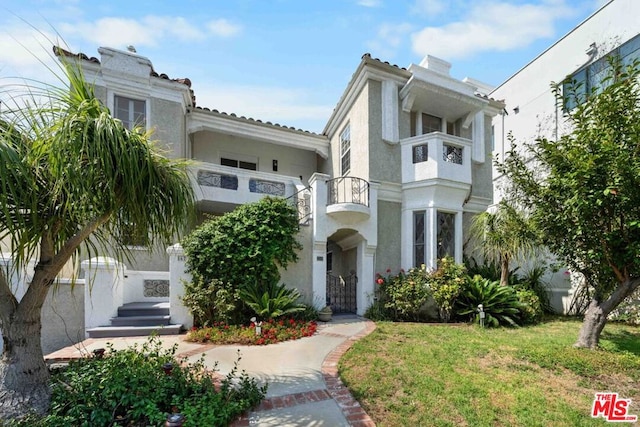 view of front of home with a balcony and a front yard