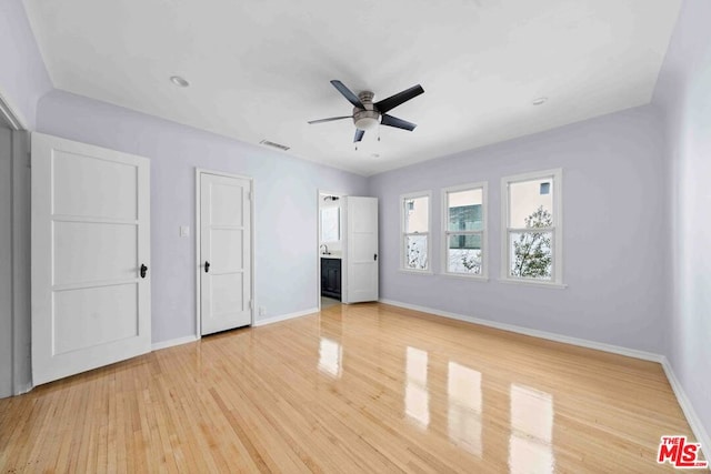 unfurnished bedroom with ceiling fan, connected bathroom, and hardwood / wood-style floors