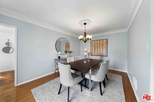 dining area with hardwood / wood-style floors, crown molding, and a chandelier