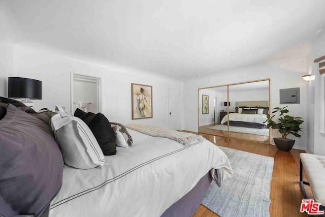 bedroom with a closet, electric panel, and wood-type flooring