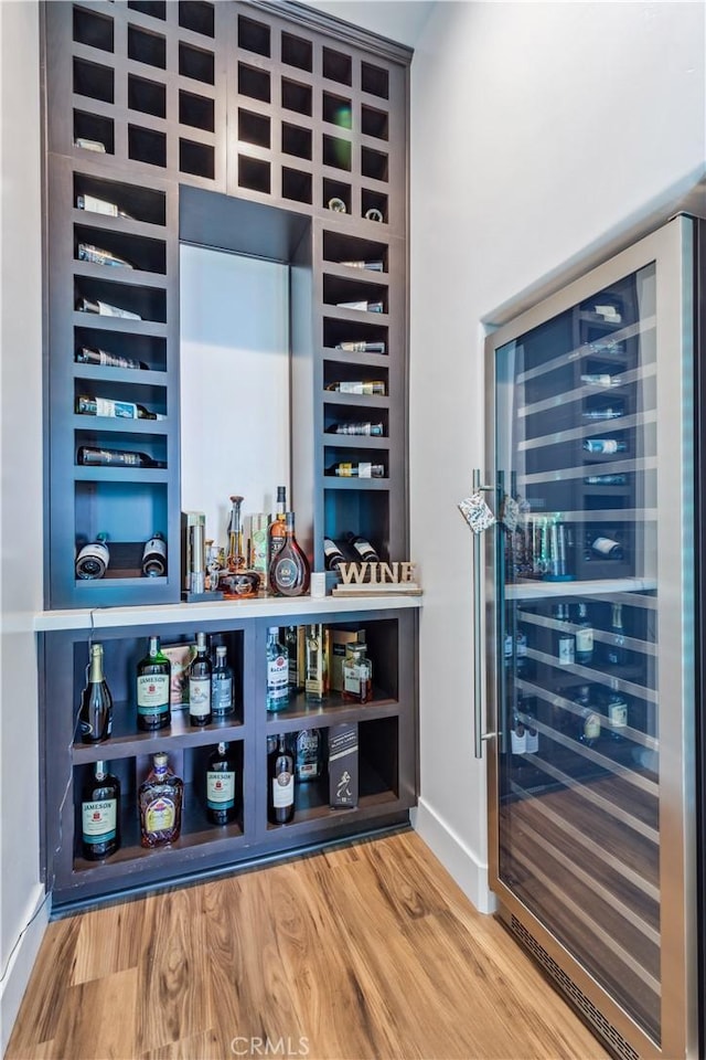 bar with wine cooler and hardwood / wood-style flooring