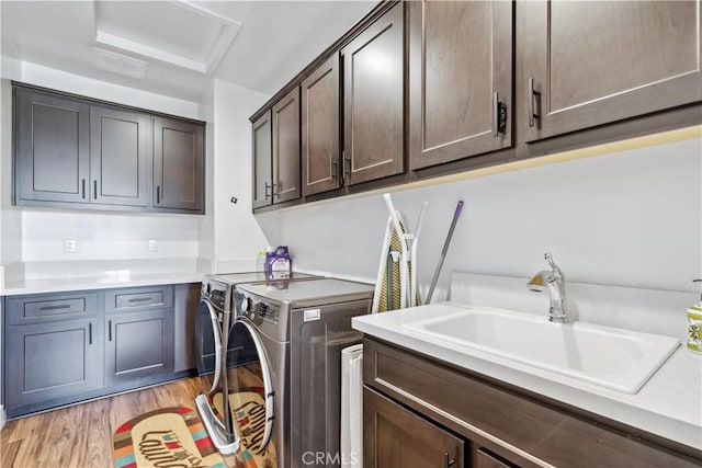 laundry area featuring sink, washing machine and dryer, cabinets, and light wood-type flooring