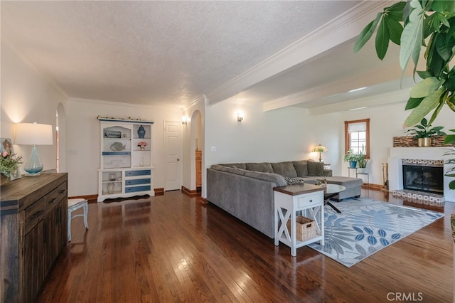 living area featuring arched walkways, crown molding, a brick fireplace, a textured ceiling, and hardwood / wood-style floors