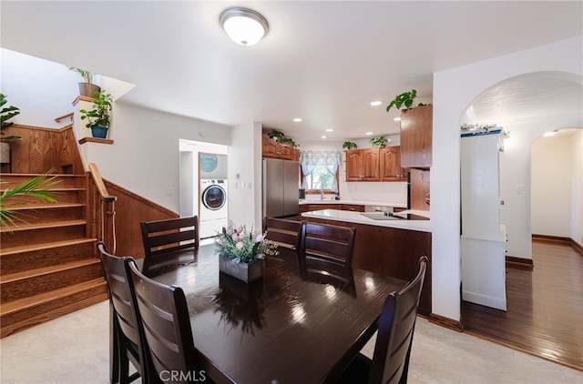 dining area with arched walkways, light wood finished floors, recessed lighting, washer / dryer, and stairs