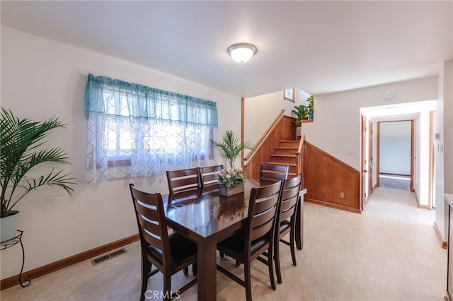 dining room with a wainscoted wall, stairs, and visible vents