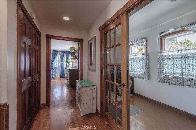 corridor with a healthy amount of sunlight, baseboards, and wood finished floors