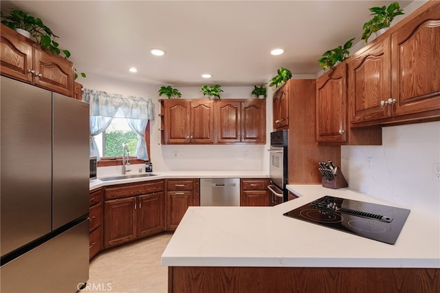 kitchen with brown cabinets, a peninsula, stainless steel appliances, a sink, and recessed lighting