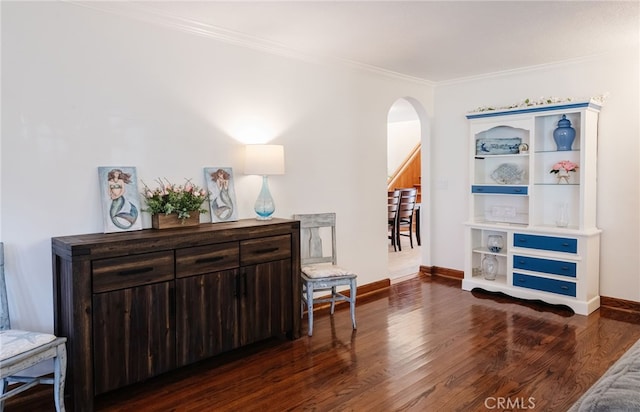 living area featuring ornamental molding, arched walkways, baseboards, and wood finished floors