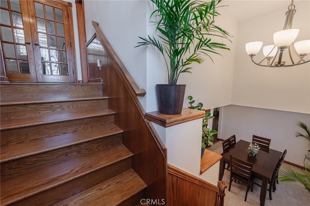 staircase with a chandelier and carpet flooring