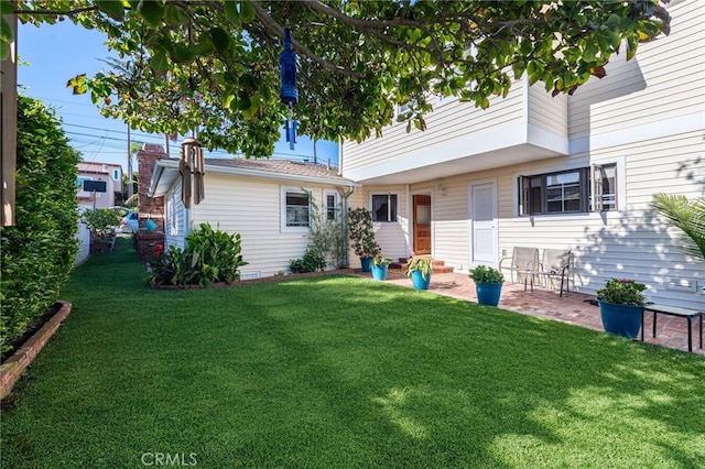 rear view of house with entry steps, a lawn, and a patio