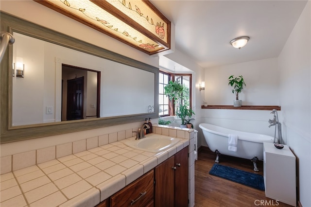 bathroom featuring a freestanding bath, wood finished floors, and vanity