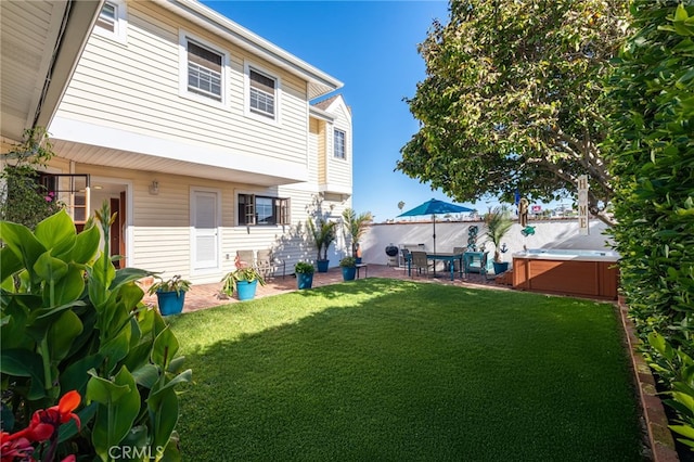 back of property with a patio area, a fenced backyard, a lawn, and a hot tub