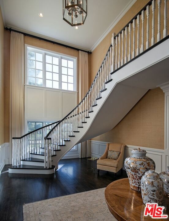 stairs with wood-type flooring, a chandelier, and crown molding