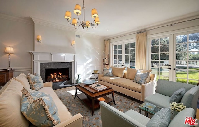 living room with a notable chandelier, ornamental molding, and french doors