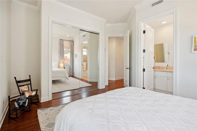 bedroom with ensuite bathroom, a closet, dark hardwood / wood-style floors, and ornamental molding