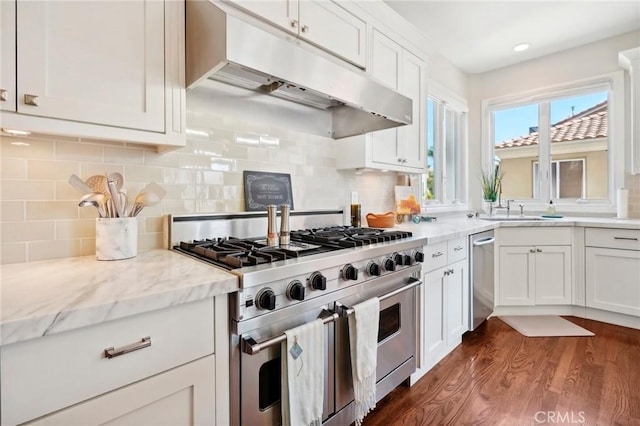 kitchen with backsplash, range with two ovens, light stone counters, dark hardwood / wood-style flooring, and white cabinetry