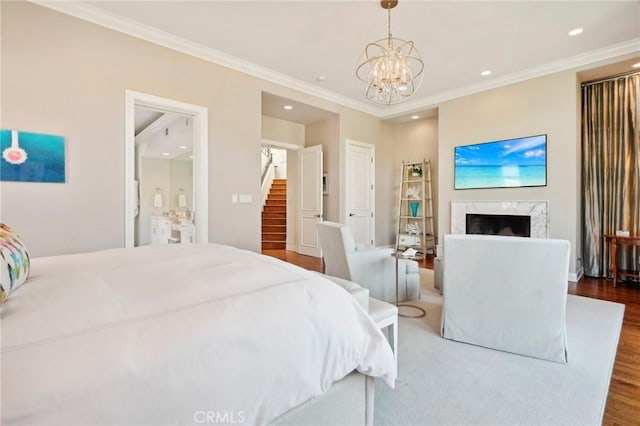 bedroom featuring dark hardwood / wood-style flooring, a fireplace, a chandelier, and ornamental molding