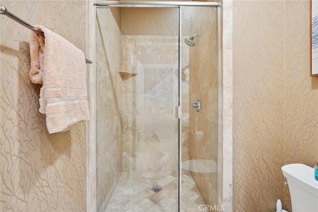 bathroom with a shower with door and toilet